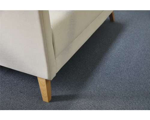 Detailweergave van een gestoffeerd meubel met stoffen bekleding en houten poten op een tapijtvloer