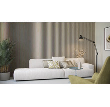 Woonkamer met houten lambrisering, bank, staande lamp en kamerplant.