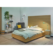 Lichte slaapkamer met bed, nachtkastje, rek en fauteuil