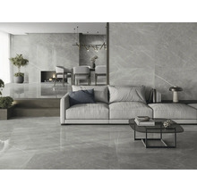 Lichte woonkamer met vloertegels en wandtegels in marmerlook, met bank, tafel en open haard.