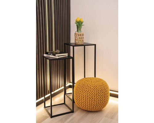 Twee bijzettafels met zwart metalen frame, een gele poef en een vaas met gele tulpen
