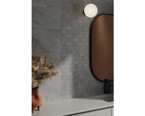 Badkamer met grijze wandtegels in steenlook, spiegel en lamp