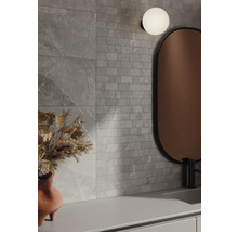 Badkamer met grijze wandtegels in steenlook, spiegel en lamp