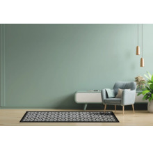 Woonkamer met fauteuil, vloerkleed met patroon en decoratie