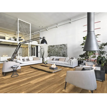Lichte woonkamer met houten vloer, witte banken, fauteuils en open haard