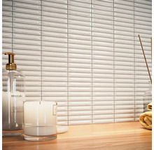 Scene met witte, langwerpige wandtegels, zeepdispenser, kaars en handdoek op een houten tafel
