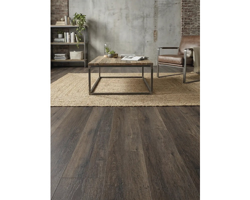 Woonkamer met houten vloer, vloerkleed, tafel, fauteuil en plank