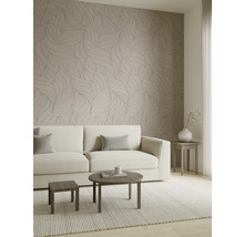 Moderne woonkamer met behang met bladmotief, een lichte bank en houten tafels op een geweven tapijt.