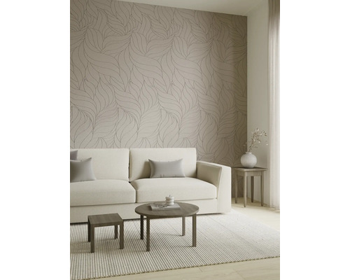 Moderne woonkamer met behang met bladmotief, een lichte bank en houten tafels op een geweven tapijt.