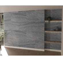 Moderne wanddecoratie met donkere natuurstenen strips, verlichte houten planken in een nis en visgraatparket.