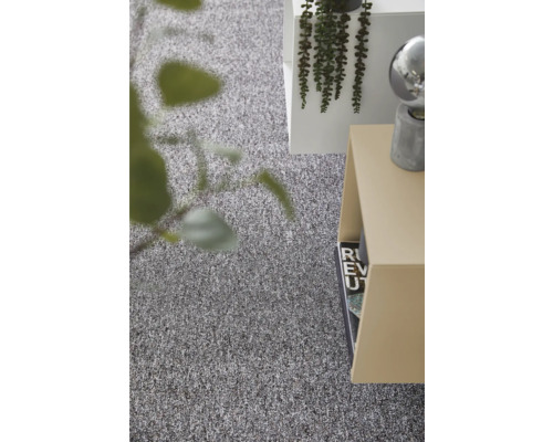 Gestructureerd grijs tapijt in een lichte, modern ingerichte kamer met bijzettafel en plant.