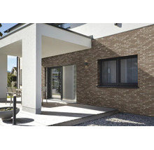 Moderne gevel met bruine steenstrips bij een terras met houten vlonder en witte kolommen.