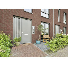 Moderne entree met grijze voordeur, bakstenen gevel, houten bankje op grind en groene beplanting.