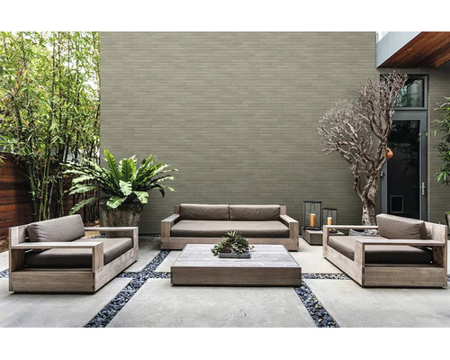 Moderne buitenruimte met houten loungeset, betonplaten, een grijze bakstenen muur en diverse planten.