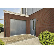 Buitengevel van een woning met steenstrips, grijze garagedeur, moderne voordeur en bestrate entree.