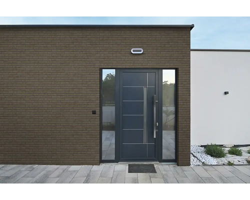 Moderne entree van een woning met een gevel van steenstrips in baksteenlook en een donkere voordeur.