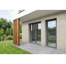 Gevel met lichtbeige steenstrips in baksteenlook, kamerhoge ramen en een terras met grijze stenen tegels.