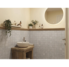 Moderne badkamer met ronde verlichte spiegel, witte waskom op rustiek houten meubel en grijze vierkante wandtegels.