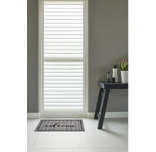 Deurmat met het opschrift Welcome voor een raam met witte shutters in een lichte, moderne hal.