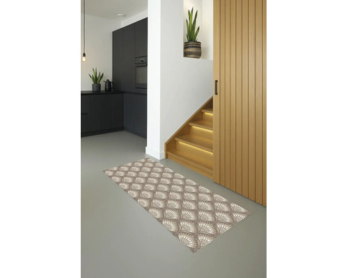 Moderne gang met een loper met patroon op een grijze vloer, een houten trap met verlichting en een donkere keuken op de achtergrond.