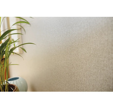 Behang met fijn visgraatmotief en textielook op een muur, naast een kamerplant.