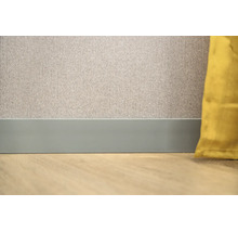 Platte plint aan een muur met behang met patroon en een vloer met houtlook.