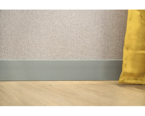 Platte plint aan een muur met behang met patroon en een vloer met houtlook.