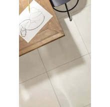 Een lichte woonruimte met grootformaat tegels op de vloer, een houten tafel met een tekening en een stoel in een minimalistische omgeving.