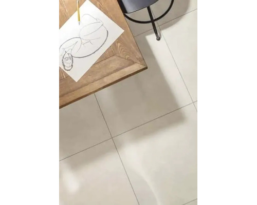 Een lichte woonruimte met grootformaat tegels op de vloer, een houten tafel met een tekening en een stoel in een minimalistische omgeving.