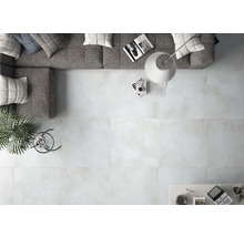 Lichte woonkamer met tegelvloer, bank, vloerlamp en tafel