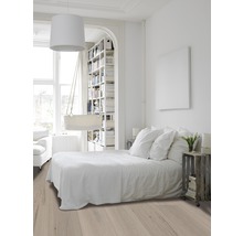 Lichte, vriendelijke slaapkamer met houten vloer, bed en boekenkast