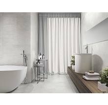 Badkamer met ligbad, wastafel en gestructureerde wandtegels