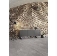 Woonkamer met dressoir, staande lamp en bakstenen muur