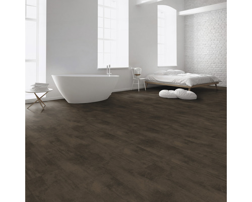 Lichte ruimte met bad, bed en donkerbruine vloer met houtlook