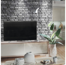 Woonkamer met gemetselde accentmuur, televisie, vloerlamp en decoratieve elementen op een salontafel
