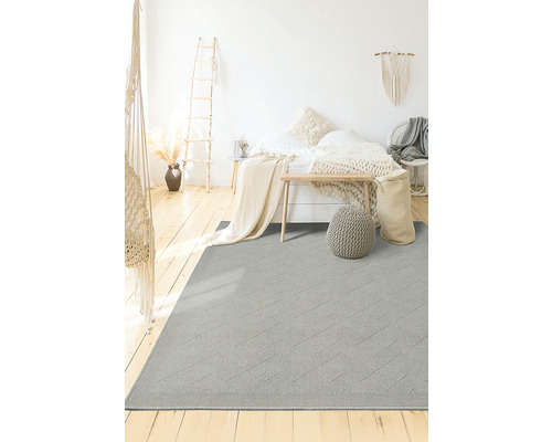 Lichte kamer met bed en grijs vloerkleed met geometrisch patroon