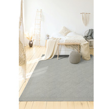 Grijs tapijt met geometrisch patroon in een slaapkamer met bed en houten vloer.