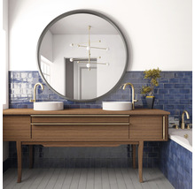 Badkamer met wastafel, ronde spiegels, kranen en blauwe tegels.