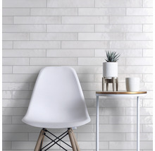 Lichte tegelwand met stoel en bijzettafel, moderne ruimte-indeling.