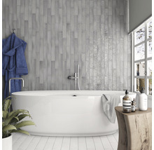 Badkamer met grijze tegels, bad, handdoek en decoratie