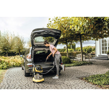 Vrouw stofzuigt het interieur van een auto met een alleszuiger.