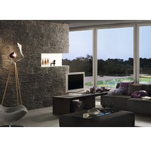 Woonkamer met stenen muur, televisie, lamp en raampartij met uitzicht op groen