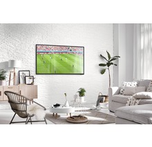 Lichte woonkamer met televisie, bank en fauteuil