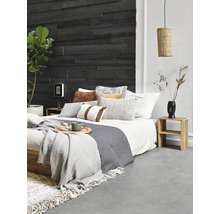 Slaapkamer met houten wand, bed, kussens, dekens, bijzettafel en lamp