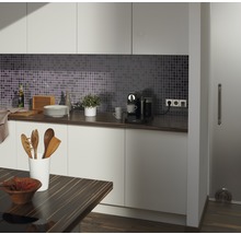 Moderne keuken met mozaïektegels, werkblad, keukengerei en koffiezetapparaat.
