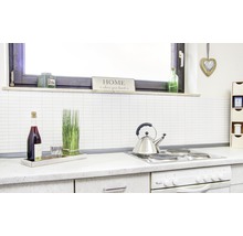 Keukenscène met kookplaat, waterkoker, fles, glas en decoratieve elementen.