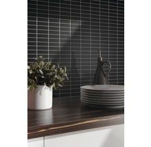 Keukenscène met zwarte wandtegels, houten werkblad, servies en decoratie