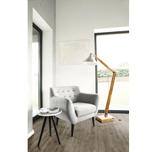 Lichte woonkamer met fauteuil, vloerlamp en bijzettafel op vloerbedekking