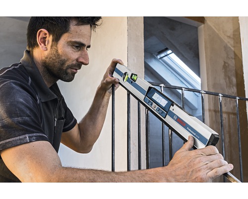 Vakman gebruikt digitale waterpas van Bosch Professional op een hek.
