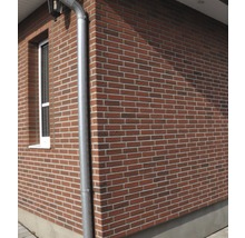 Buitenkant van een huis met bakstenen gevel en regenpijp